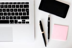 Image of laptop, pens, and note